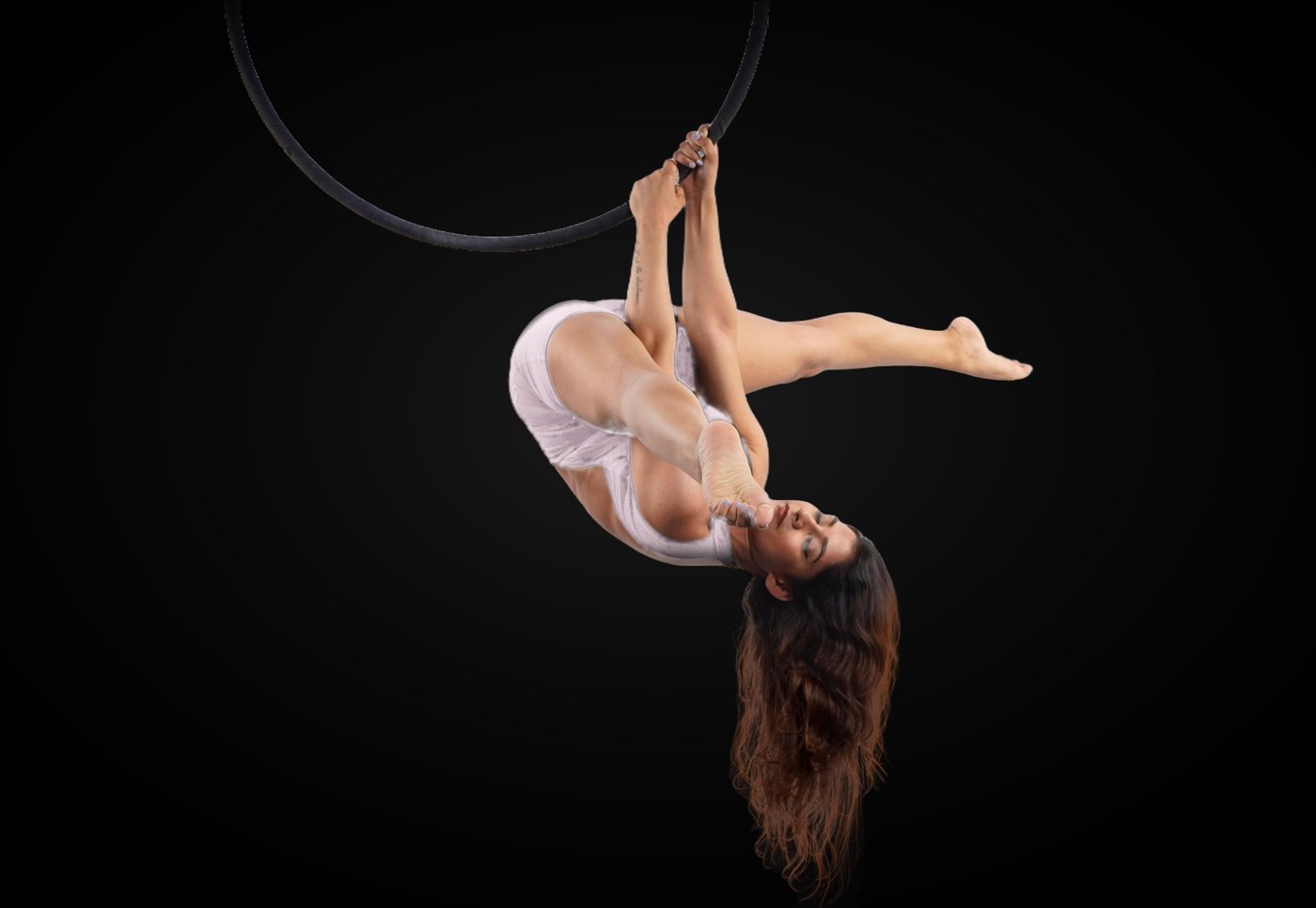 Roshani in a lilac bodysuit in an inverted tuck beneath an aerial hoop